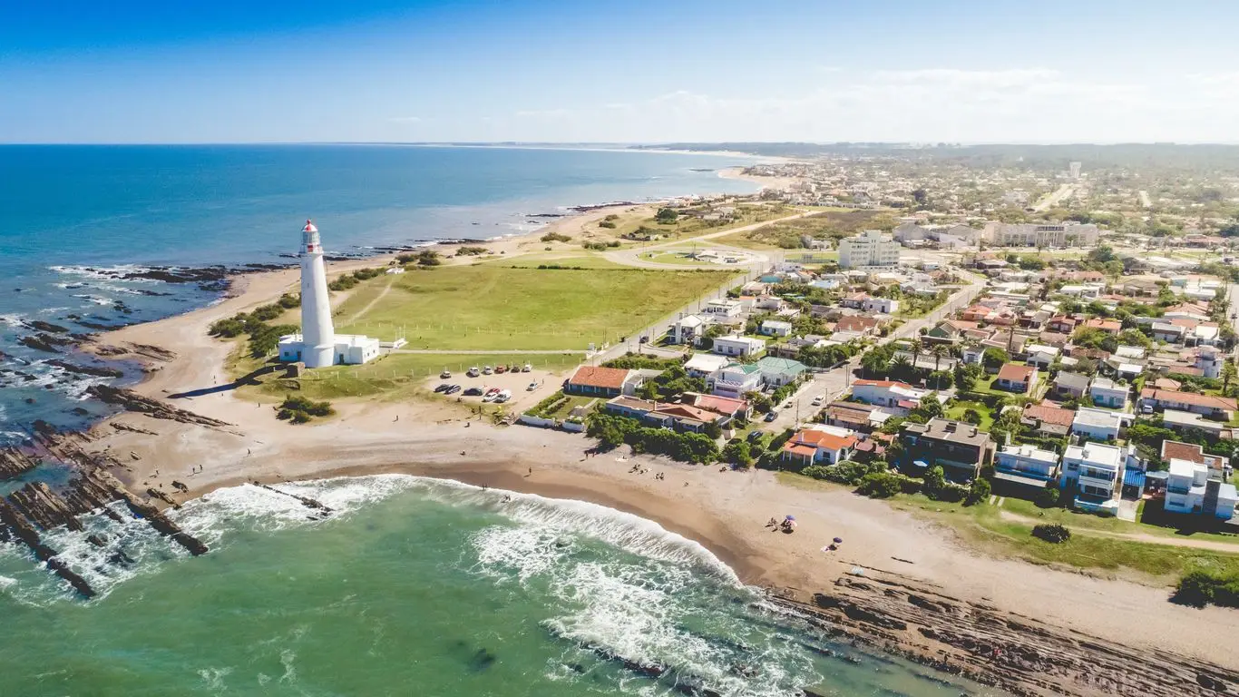 El faro de La Paloma sobre la costa rocosa, con playas amplias de arena clara.